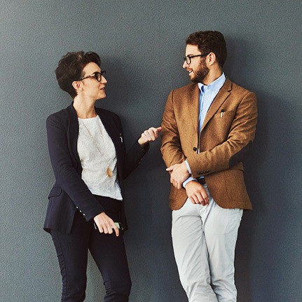 man and woman talking against a dark wall