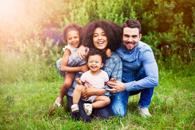 Mother, father, and 2 daughters smile outside