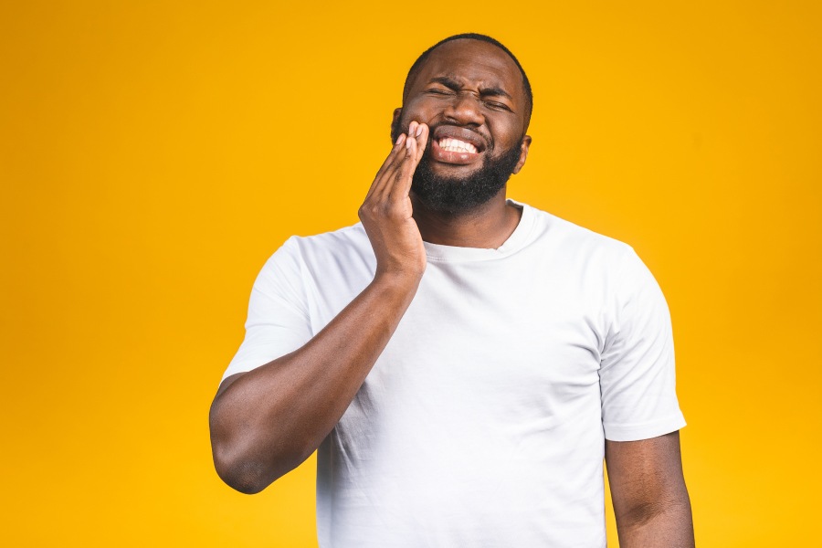 Man in a white shirt against a yellow wall cringes