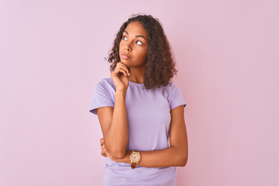 brunette woman in a lavender shirt wonders how long does a tooth extraction take at the dentist