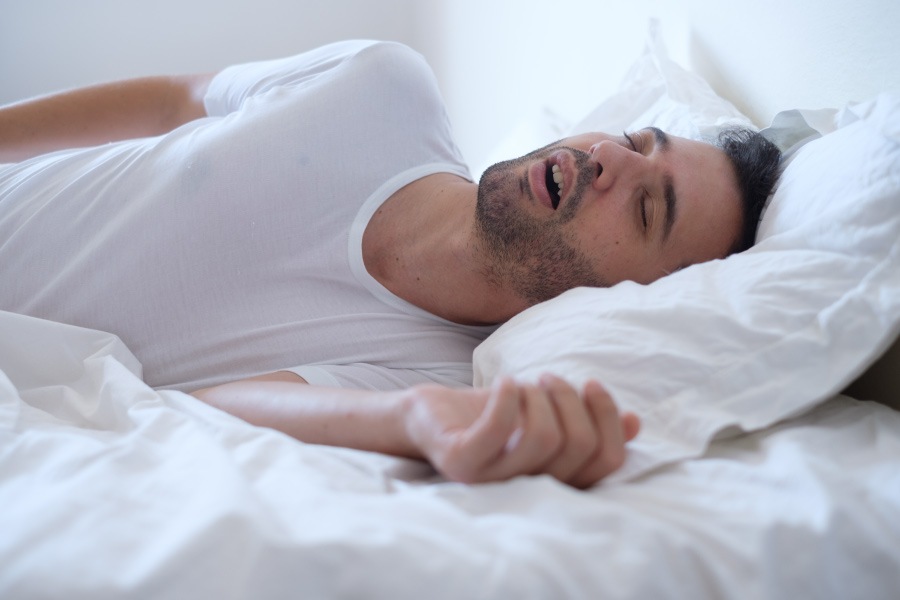 Man with obstructive sleep apnea sleeps fitfully on white sheets in Fort Smith, AR