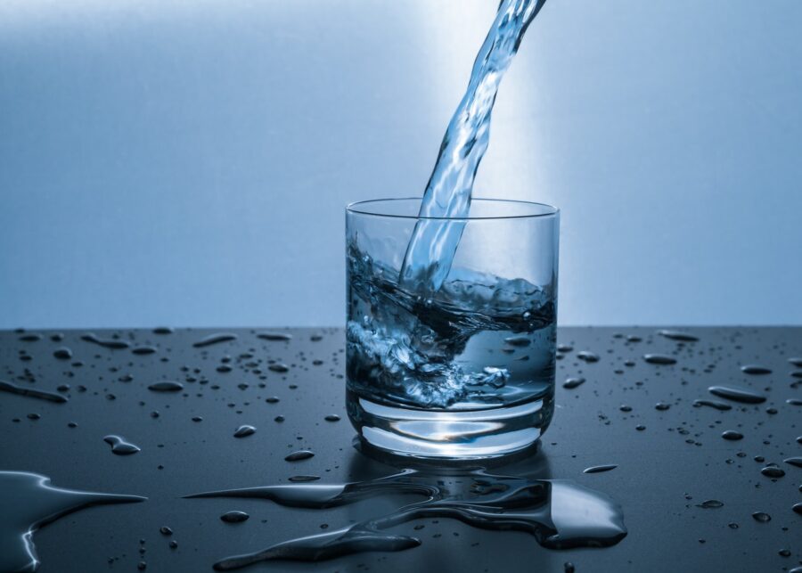 Water being poured into a short glass of water that is good for teeth