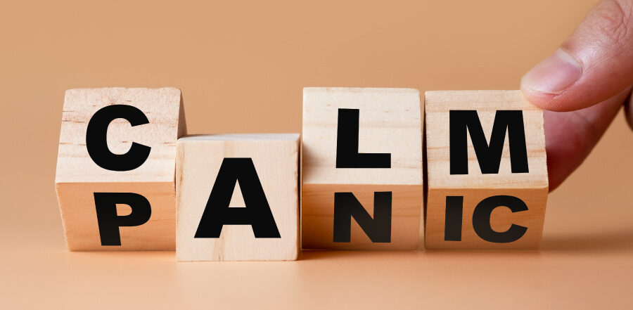 A finger turns wooden blocks from PANIC to CALM against a brown background 