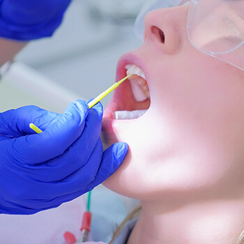 dental patient receiving an application of fluoride on her teeth