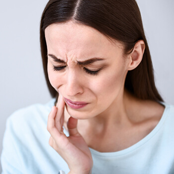 woman holding her jaw in pain